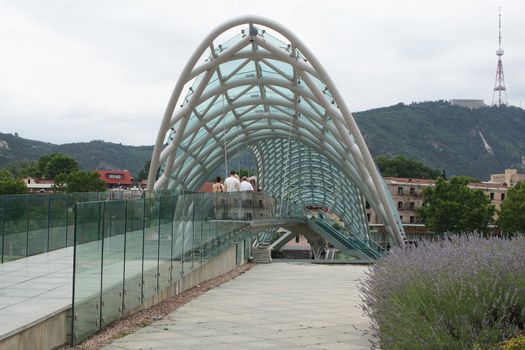 TBILISI, GEORGIA - JUNE 28, 2014: People crossing the Bridge of Peace on June 28, 2014 in Tbilisi, Georgia, Europe