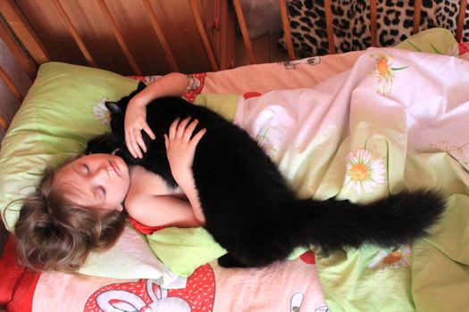 little girl playing with her cat in her bed