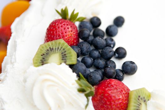 White frosted cake covered with fresh fruit toppings. Shallow depth of field.