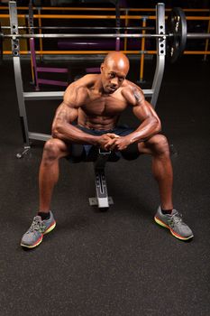 Weight lifter sitting at the bench press about to lift a barbell.