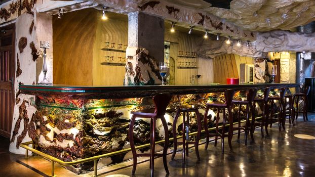 A beautifully decorated empty bar with a colorful counter and bar stools