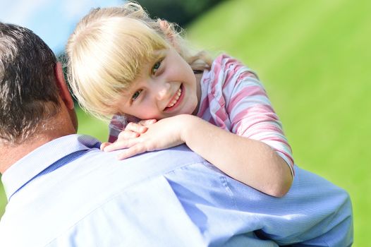 Smiling girl resting on her father's shoulder