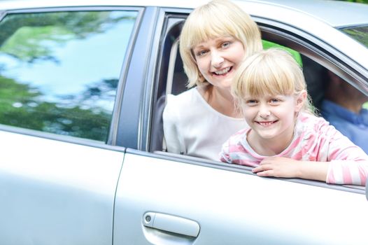 Smiling mother and daughter in car looking out windows