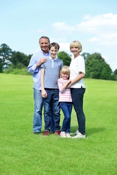 Smiling family of four posing at the meadow