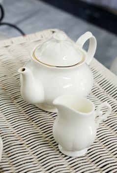 Teapot with little milk jar on weave texture background
