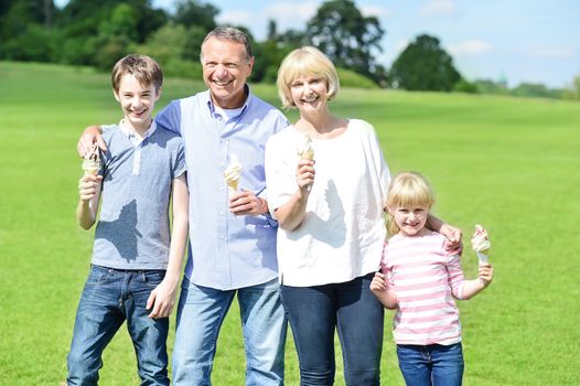 Cheerful family of four eating ice cream, outdoors