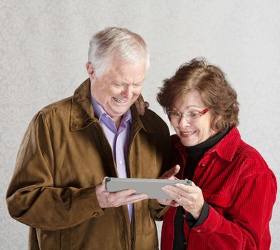Senior male and female excited with computer tablet