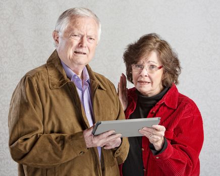 Two mature adults confused with tablet computer