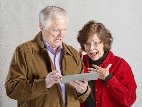 Shocked man and woman looking at computer tablet