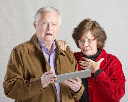 Startled man and woman looking at computer tablet