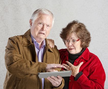 Embarrassed senior man covering his tablet computer