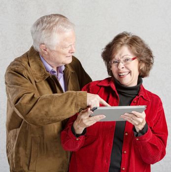 Confused man pointing at smiling womans tablet