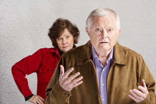 Frustrated older man with hands up and annoyed woman