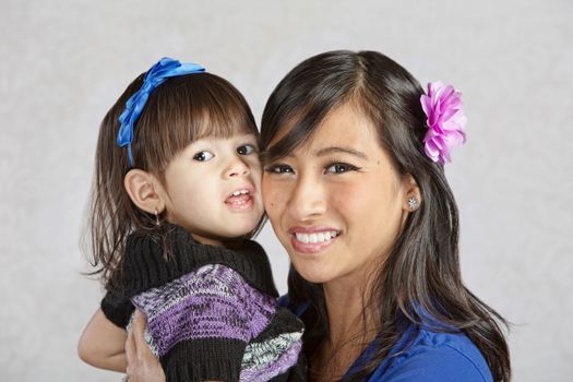 Beautiful young Asian mother holding little girl
