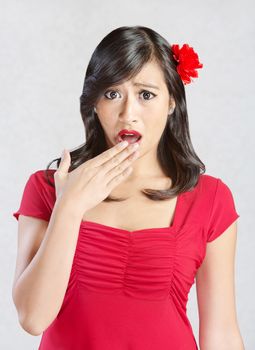 Shocked young Hispanic woman in red with flower in  hair