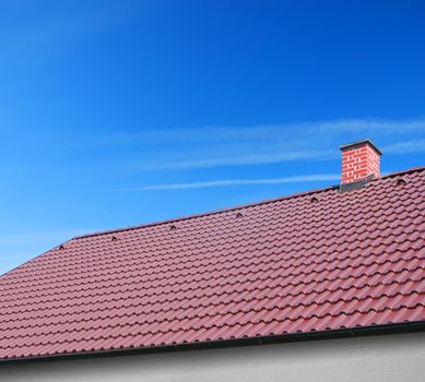 roof with brown tiles on a background of blue sky, new roof