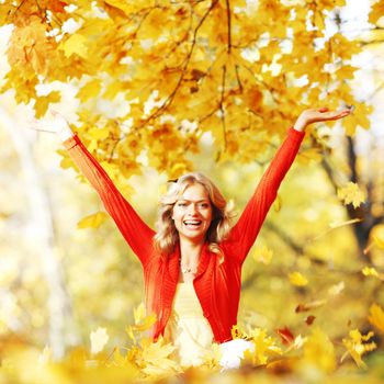 Happy woman in autumn park drop up leaves