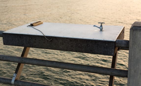 Metal table with tap or faucet for washing and cleaning fish with brush on pier off coast of Florida