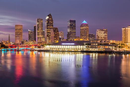 Florida skyline at Tampa with the Convention Center on the riverbank. Sun is just setting at dusk giving a fiery glow to the night sky.