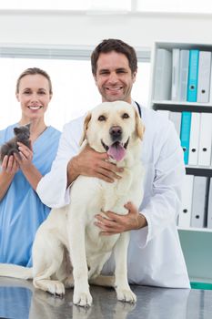 Portrait of happy veterinarians with dog and kitten in hospital