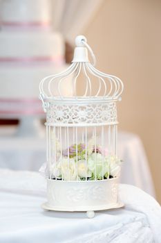 White cage with roses decorates a wedding reception