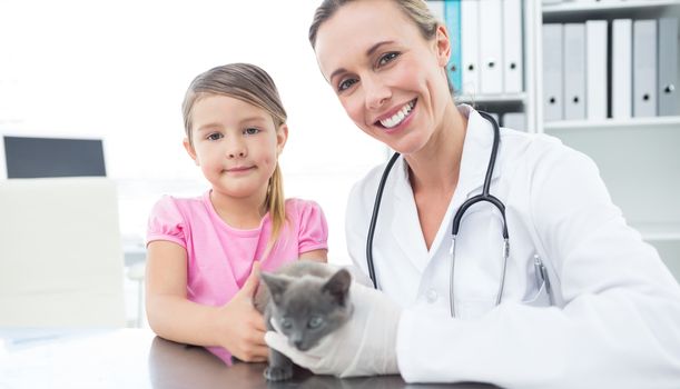Portrait of female vet and girl with kitten in clinic