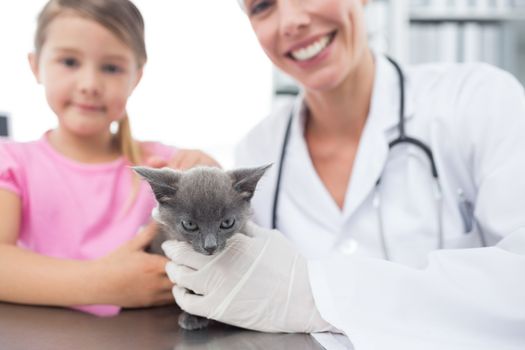 Happy female veterinary and girl with kitten in hospital