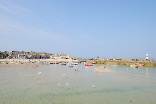 St Ives in Cornwall on a sunny day with seagulls flying and fishing boats in the background