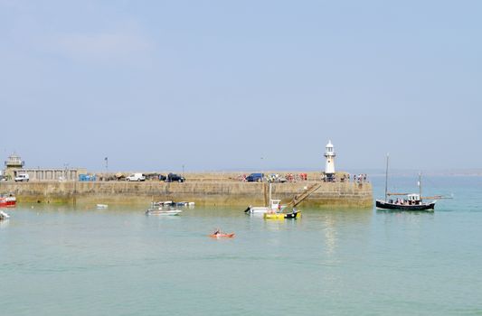 Lighthouse and boats visible in a harbour in St Ives, Cornwall, England on a sunny day in the summer.