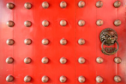 Ornate doorways to traditional chinese temple with guardian door knockers