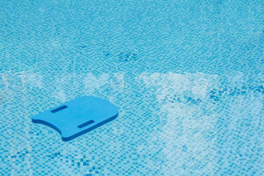 Blue kick board in swimming pool