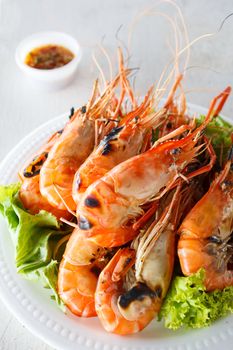 Grilled prawns with seafood sauce on white wood