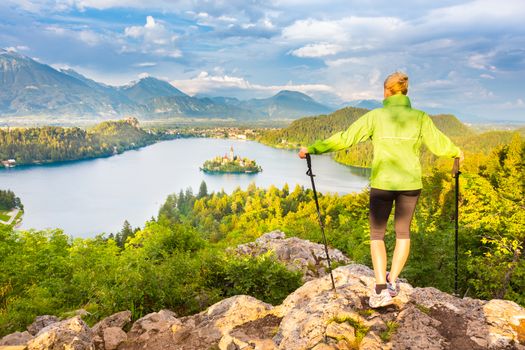 Young spoty active lady with hiking sticks admiring beautiful nature around Bled Lake in Julian Alps, Slovenia. 