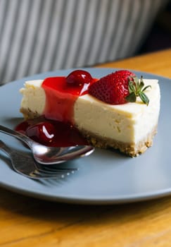 Strawberry Cheesecake with spoon and fork on wooden table