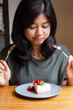 Young beautiful woman with a cake in cafe