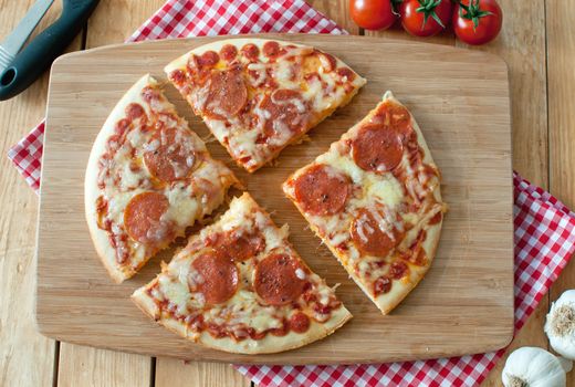 Delicious rustic Italian pizza slices with mozzarella cheese on top of a wooden chopping board 