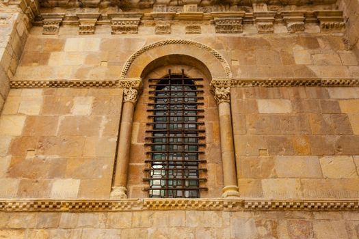 Delightful romanesque art window along with forged protection in the wall of the San Isidoro collegiate church in Leon ,Spain