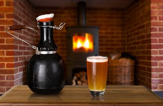 Large 64 fluid ounce four pint growler bottle with a glass of cold beer or ale in front of fire. Used by microbreweries to serve beer for home consumption