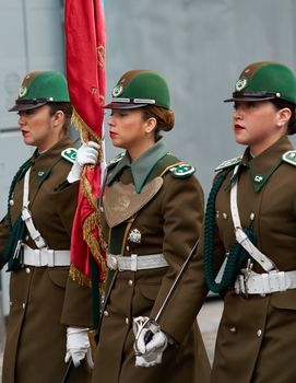 Female members of the Carabineros marching with a ceremonial flag as part of the changing of the guard ceremony at La Moneda in Santiago, Chile