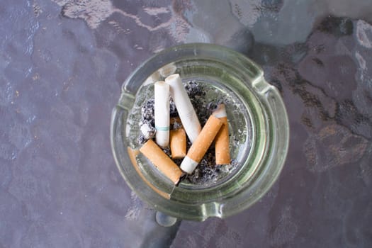 Overhead of burning cigarette in ashtray.