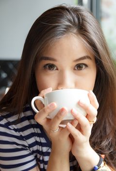 Close up portrait of woman smiling and drinking coffee