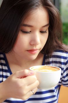 Asian woman drinking coffee in a cafe