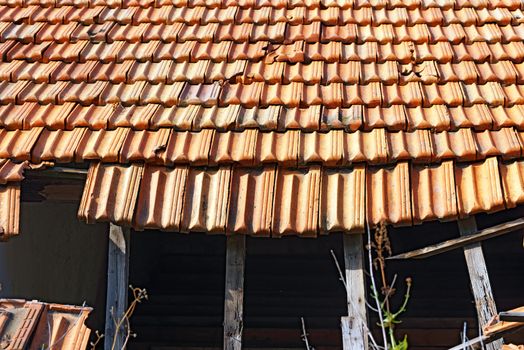 Detail of a damaged and abandoned roof with broken tiles and beams