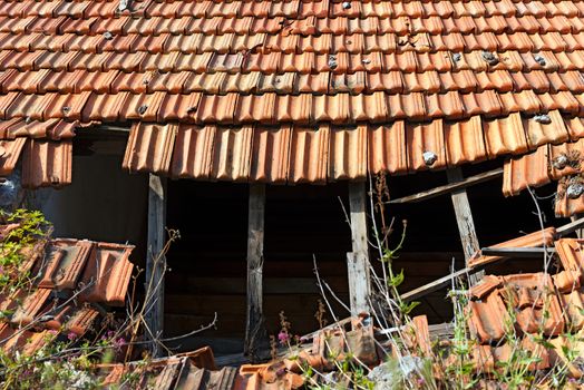 Detail of a damaged and abandoned roof with broken tiles and beams