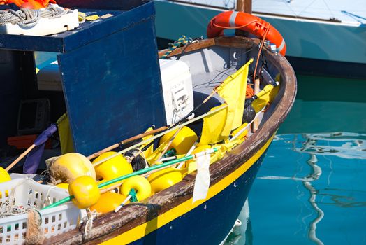 Blue and yellow small fishing boat with fishing equipment docked in port - Lerici, La Spezia, Liguria, Italy