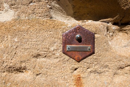 Rusty doorbell button on brown stone wall in San Gimignano town (UNESCO heritage), Siena, Tuscany, Italy