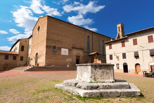 Church of Sant'Agostino in Romanesque and Gothic style (1298) and an old water well - San Gimignano, Siena, Tuscany, Italy