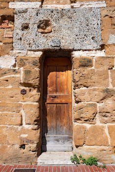 Detail with wooden door, entrance to the medieval tower in San Gimignano town (UNESCO heritage), Siena, Tuscany, Italy