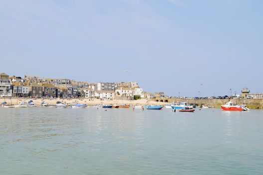 Cornish town by the sea on a sunny summer day, with boats moored in the harbour