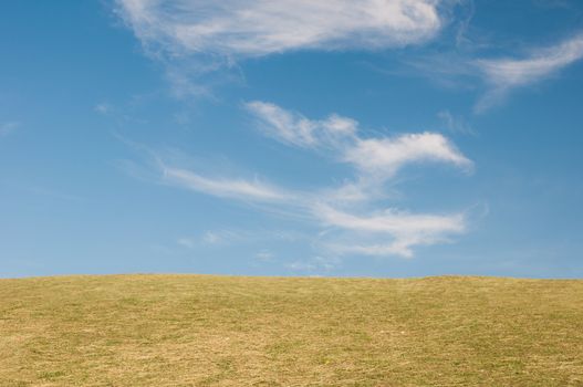 Green sloping  meadows and clouds with blue sky